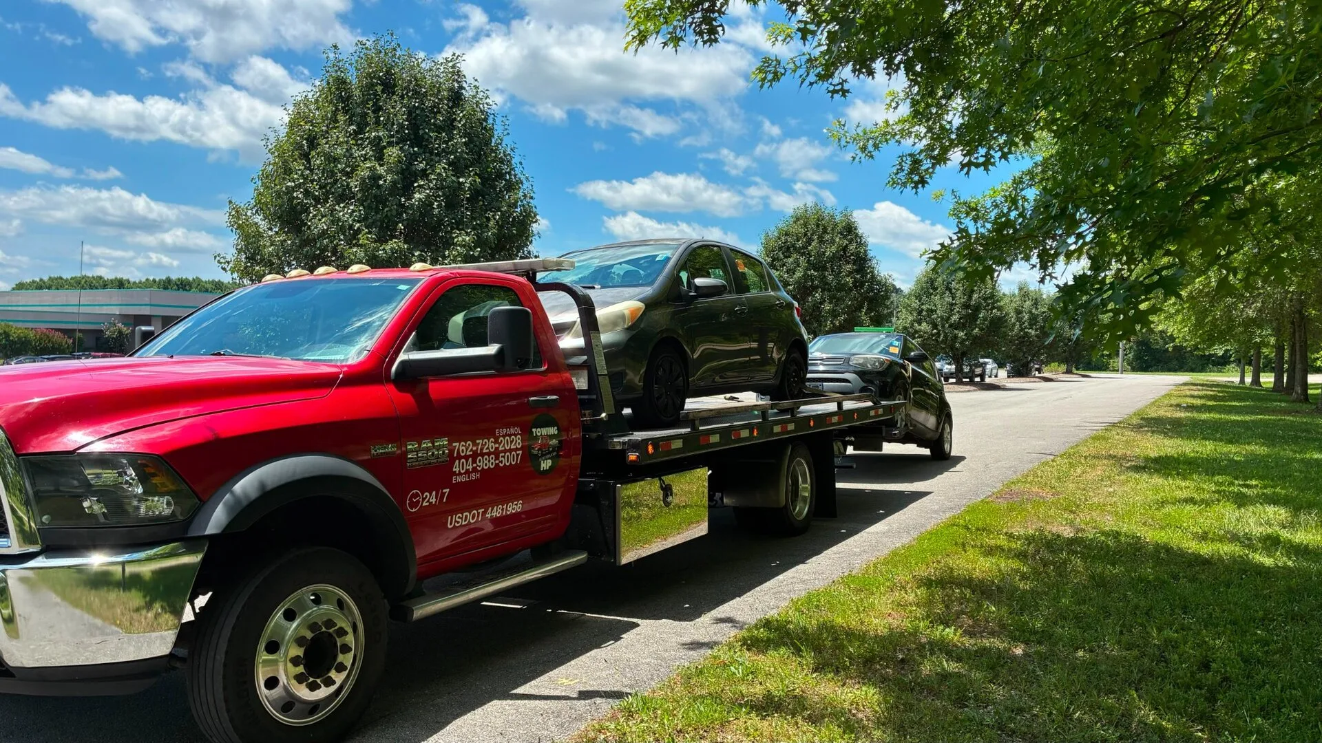 Red Ram flatbed tow truck transporting two vehicles in Norcross